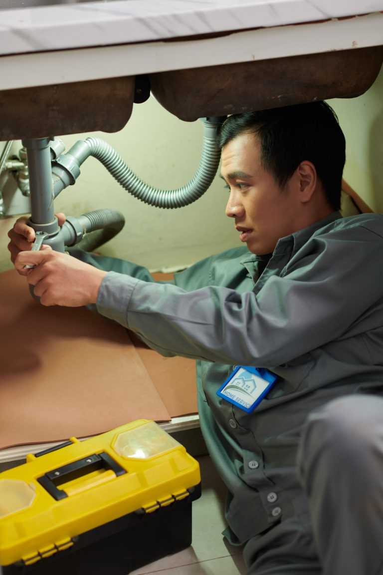 Plumber loosening slip nut on trap arm assembly and continuous waste tee and wiggling trap free